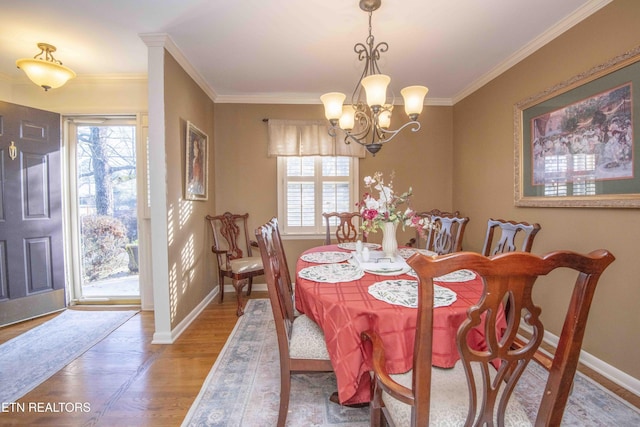 dining space featuring a notable chandelier, a healthy amount of sunlight, wood-type flooring, and crown molding