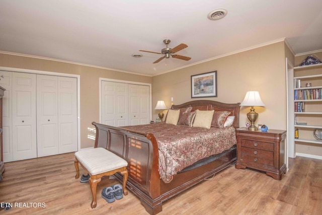 bedroom with two closets, light hardwood / wood-style flooring, ceiling fan, and ornamental molding