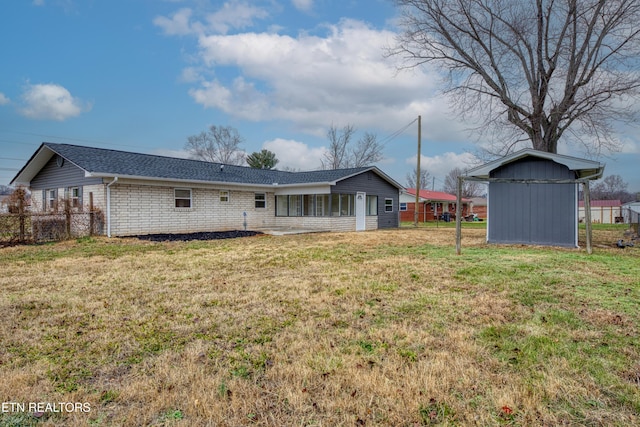 back of property with a lawn and a storage unit