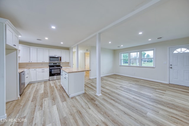 kitchen with a center island, white cabinetry, stainless steel appliances, and light hardwood / wood-style flooring