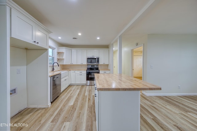 kitchen with wood counters, stainless steel appliances, sink, light hardwood / wood-style floors, and white cabinetry