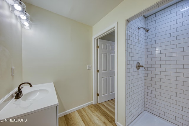 bathroom with hardwood / wood-style flooring, vanity, and a tile shower