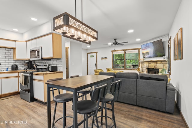 kitchen featuring ceiling fan, stainless steel appliances, pendant lighting, decorative backsplash, and white cabinets