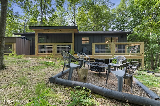 rear view of property featuring a shed and a fire pit