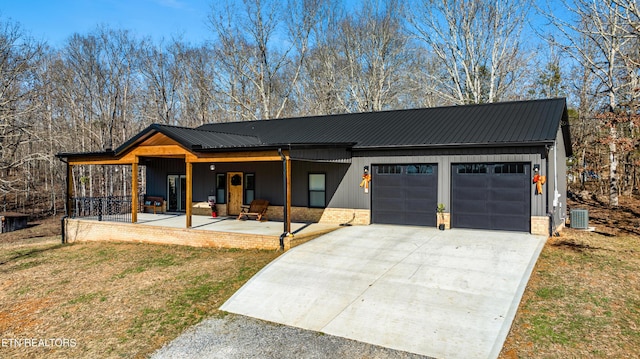 modern inspired farmhouse with central AC unit, a garage, a porch, and a front yard