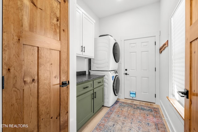 laundry area featuring cabinets and stacked washer and clothes dryer