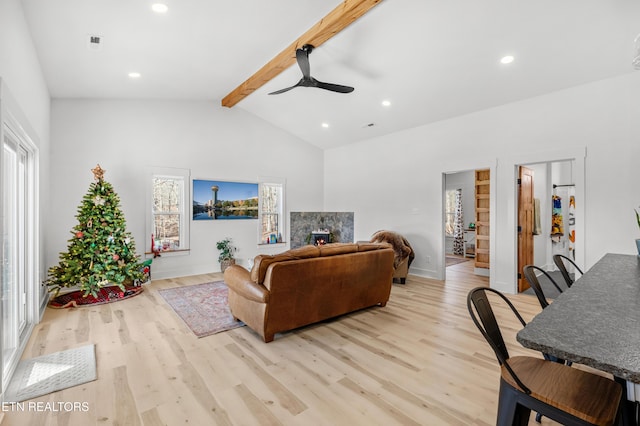 living room with vaulted ceiling with beams, ceiling fan, and light wood-type flooring