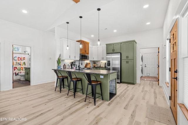 kitchen featuring a kitchen bar, appliances with stainless steel finishes, light wood-type flooring, decorative light fixtures, and white cabinetry