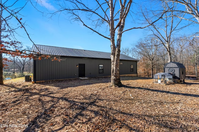 back of house featuring cooling unit and a shed