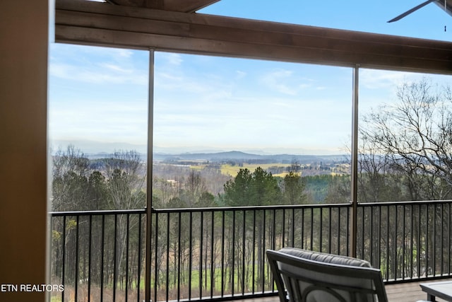 sunroom / solarium with a mountain view and ceiling fan