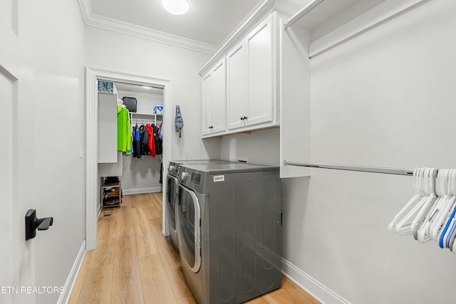 laundry room featuring cabinets, ornamental molding, light wood-type flooring, and washing machine and clothes dryer