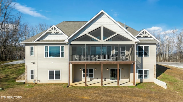 rear view of house featuring a lawn, a sunroom, and a patio