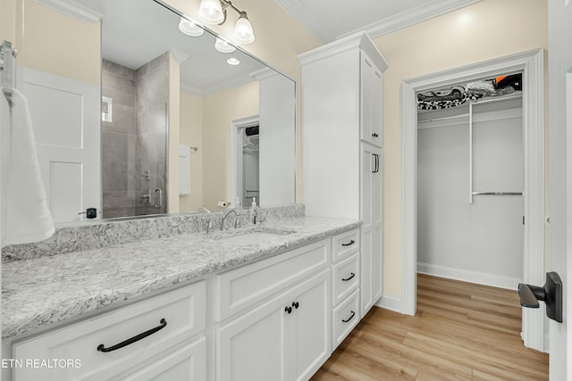 bathroom with hardwood / wood-style floors, vanity, a shower with door, and ornamental molding