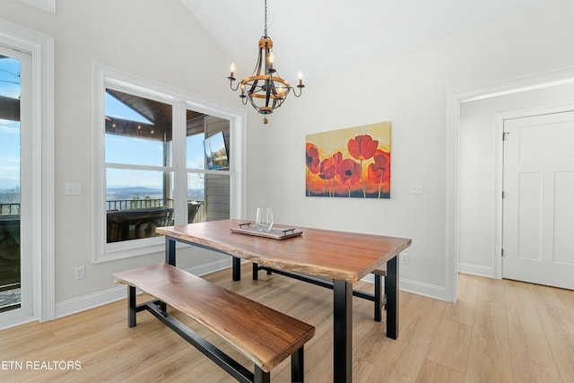 dining room featuring a notable chandelier, light hardwood / wood-style floors, and vaulted ceiling