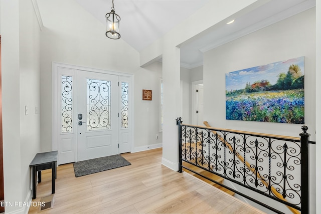 foyer featuring vaulted ceiling, ornamental molding, and light hardwood / wood-style flooring