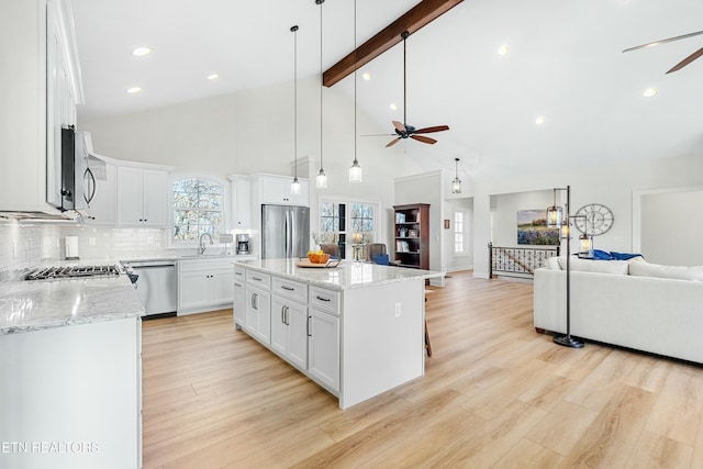 kitchen featuring a center island, appliances with stainless steel finishes, decorative light fixtures, beam ceiling, and white cabinetry