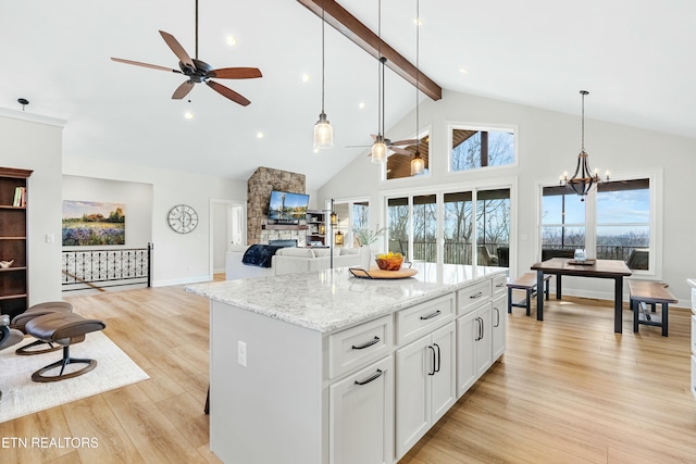 kitchen featuring white cabinets, a center island, hanging light fixtures, and light hardwood / wood-style flooring