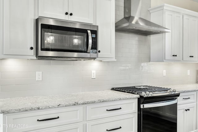 kitchen with white cabinets, decorative backsplash, gas stove, and wall chimney exhaust hood