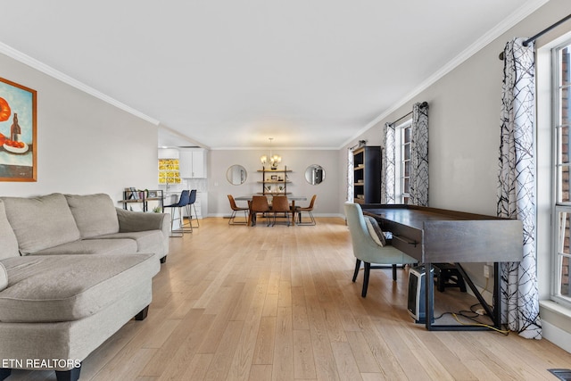 living room with light hardwood / wood-style flooring, ornamental molding, and an inviting chandelier