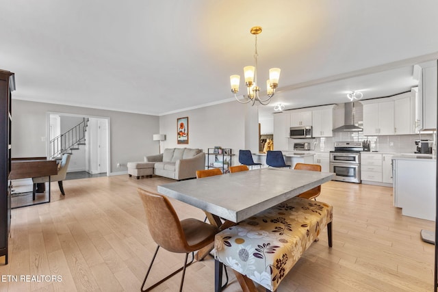 dining room featuring a chandelier, light hardwood / wood-style flooring, and crown molding