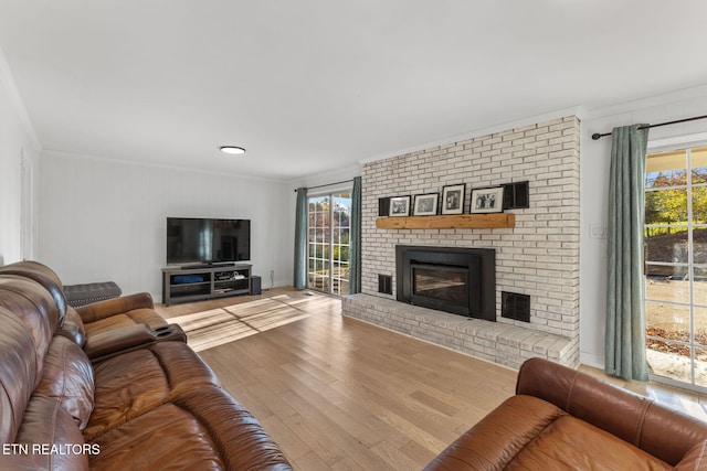 living room with hardwood / wood-style floors, a brick fireplace, and ornamental molding