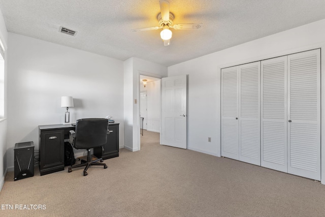 home office with a textured ceiling, ceiling fan, and light carpet