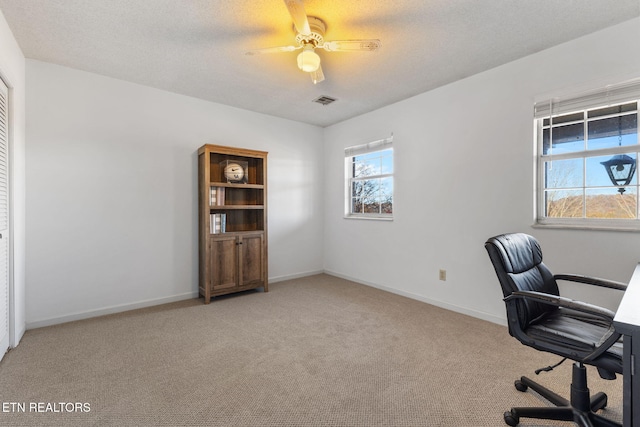 unfurnished office featuring ceiling fan, carpet floors, and a textured ceiling