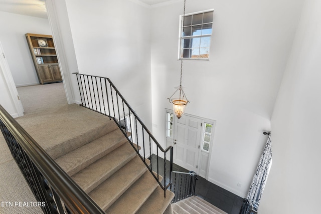 stairway with a chandelier, a high ceiling, carpet floors, and a wealth of natural light