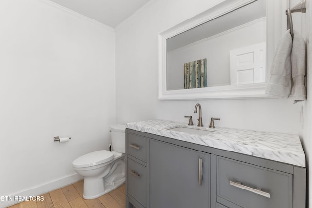 bathroom with crown molding, toilet, vanity, and hardwood / wood-style flooring