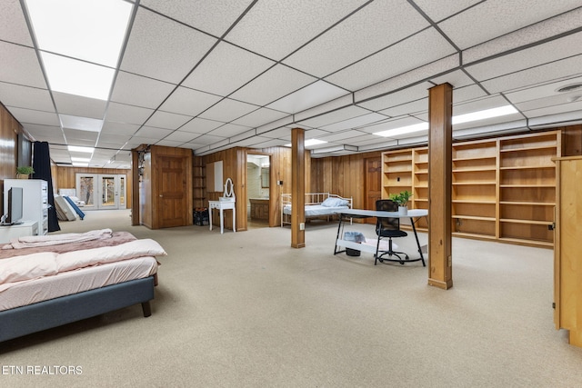 bedroom featuring carpet flooring, a drop ceiling, and wood walls