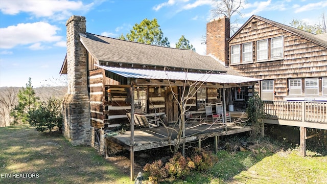 back of house with a shingled roof and a chimney