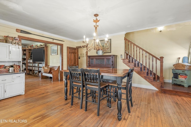 dining area with crown molding, light wood finished floors, a chandelier, baseboards, and stairs