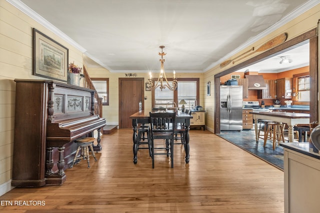 dining room featuring ornamental molding, dark wood-type flooring, a notable chandelier, and a healthy amount of sunlight