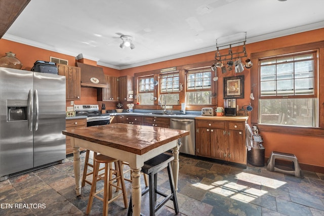 kitchen featuring custom exhaust hood, a sink, appliances with stainless steel finishes, and stone tile flooring