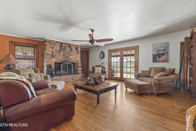 living area featuring light wood-style flooring, a fireplace, ceiling fan, and french doors