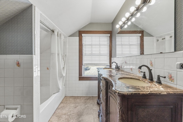 bathroom with vaulted ceiling, a sink, and tile walls