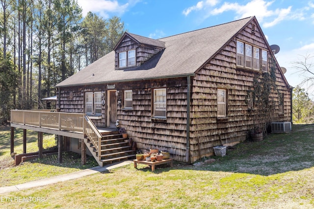 view of front facade with stairway, roof with shingles, a wooden deck, and a front lawn