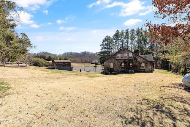 view of yard featuring a water view, fence, and an outdoor structure