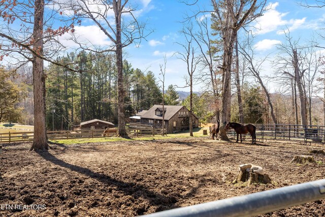 view of yard featuring an outbuilding, a rural view, and fence