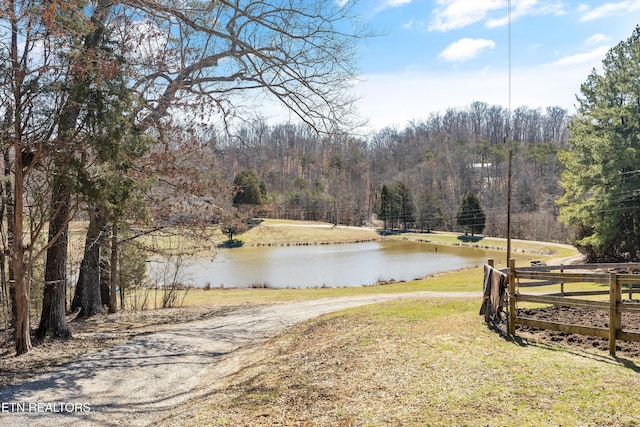 property view of water featuring a forest view and fence