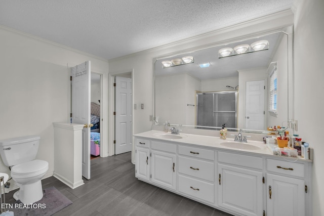 bathroom featuring hardwood / wood-style floors, a textured ceiling, toilet, a shower with door, and vanity