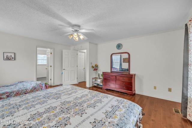 bedroom with a textured ceiling, dark hardwood / wood-style floors, ceiling fan, and crown molding