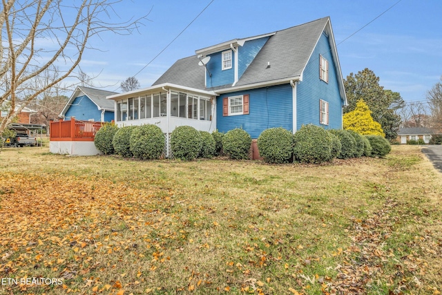 rear view of house with a lawn, a wooden deck, and a sunroom