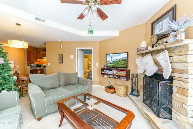 carpeted living room featuring a fireplace and ceiling fan