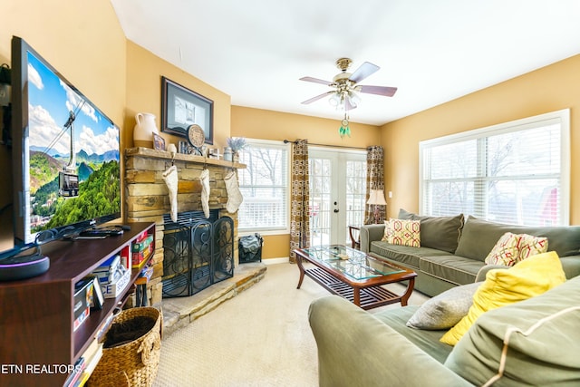 carpeted living room with a fireplace, ceiling fan, and french doors