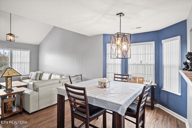 dining space featuring a notable chandelier, lofted ceiling, dark wood-type flooring, and a wealth of natural light