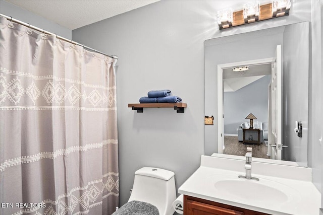 bathroom featuring vanity, a textured ceiling, toilet, and walk in shower