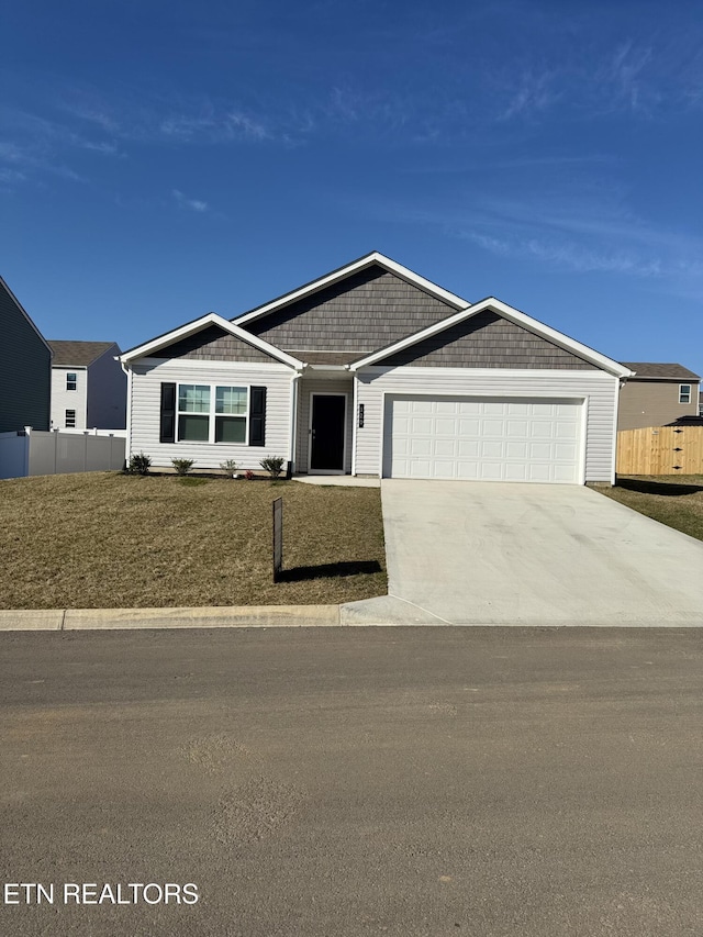 view of front of house with driveway, a garage, and fence