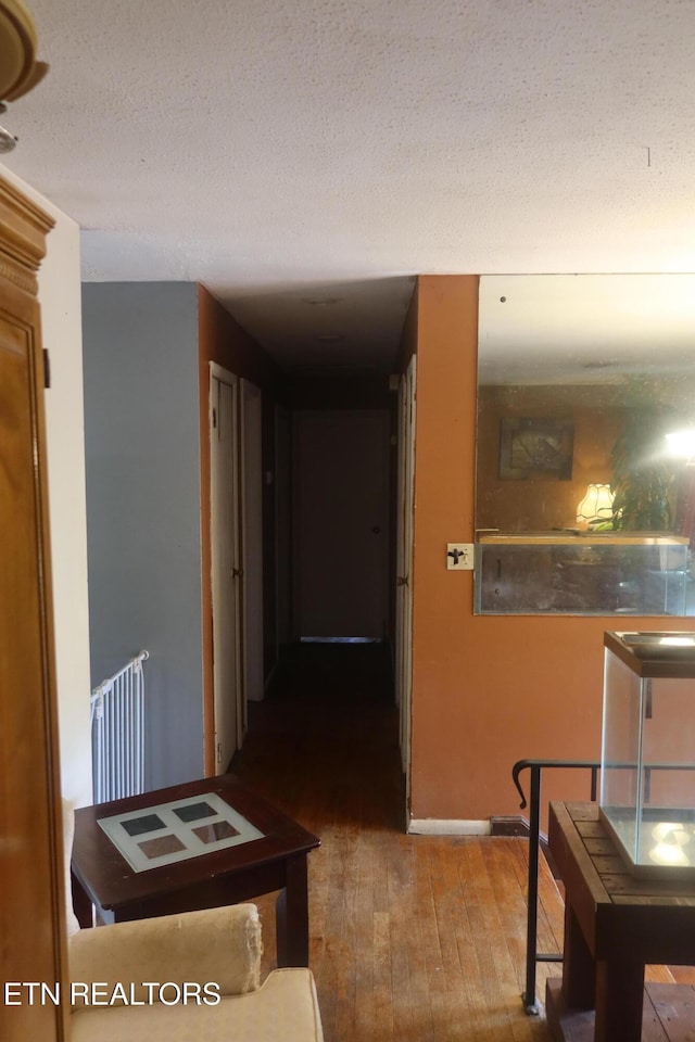 hallway with hardwood / wood-style floors, radiator heating unit, and a textured ceiling