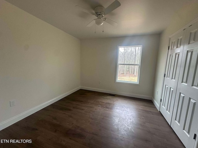 unfurnished bedroom with ceiling fan and dark wood-type flooring